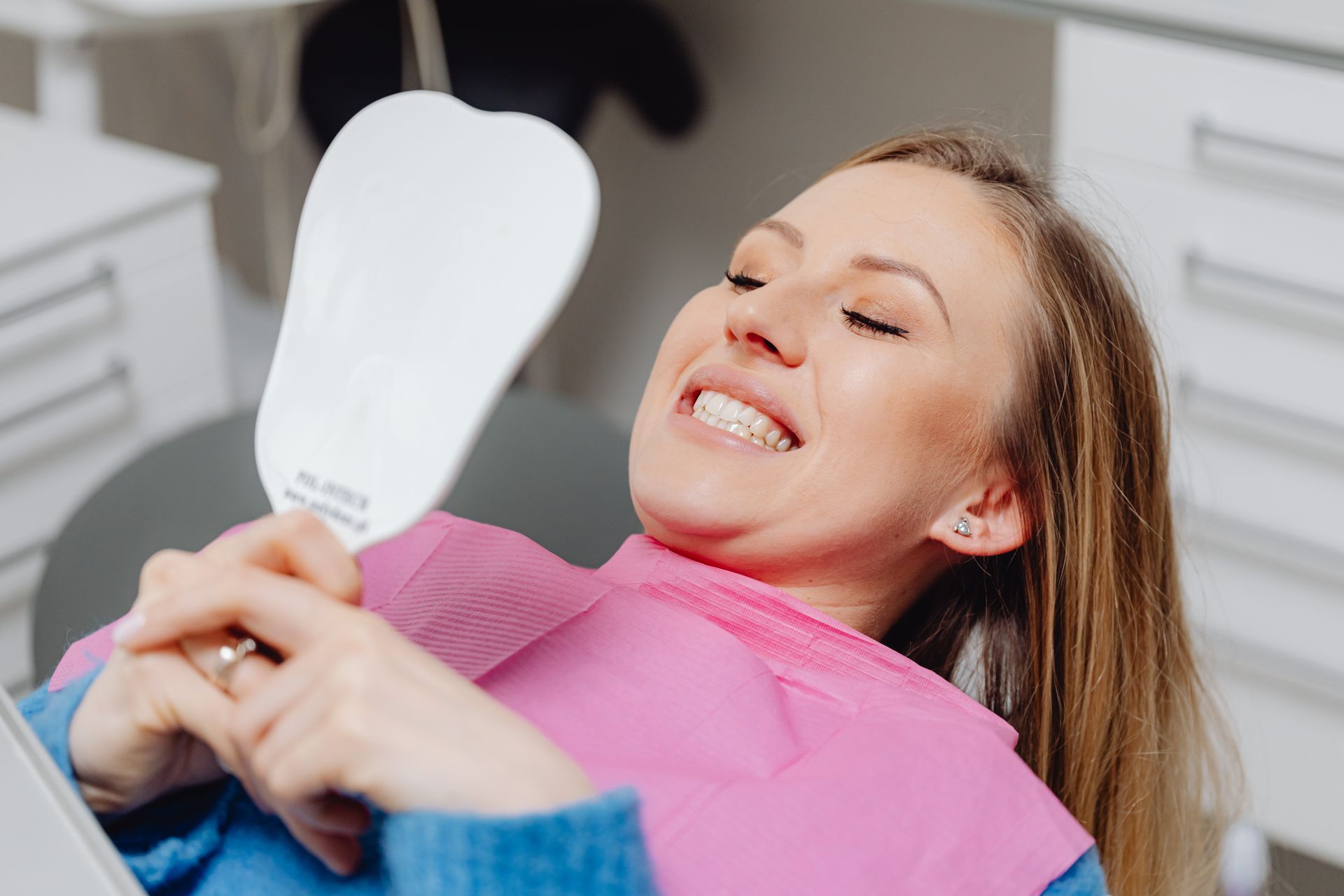 Dental patient checking smile in mirror after endodontic treatment